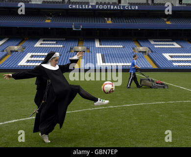 I membri del cast di Sister Act: The Musical, vestiti da suore, si riscaldano per una sessione di allenamento con il manager del Chelsea Guus Hiddink allo Stamford Bridge Stadium di Londra. Foto Stock