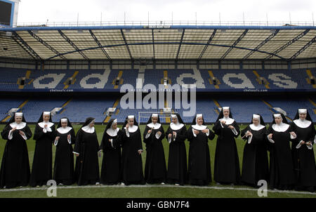 I membri del cast di Sister Act: The Musical, si veste da monache, aspettano una sessione di allenamento con il manager del Chelsea Guus Hiddink allo Stamford Bridge Stadium di Londra. Foto Stock