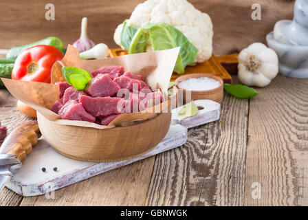 Materie di vitello tagliato a pezzi con le verdure e gli altri ingredienti già pronti da cuocere su legno tavolo rustico, cucina organica concept Foto Stock