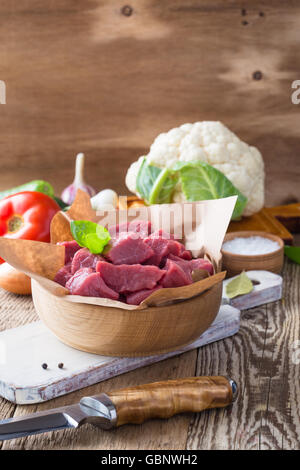 Materie di vitello tagliato a pezzi con le verdure e gli altri ingredienti già pronti da cuocere su legno tavolo rustico, cucina organica concept Foto Stock