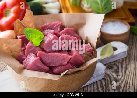 Materie di vitello tagliato a pezzi con le verdure e gli altri ingredienti già pronti da cuocere su legno tavolo rustico, cucina organica concept Foto Stock