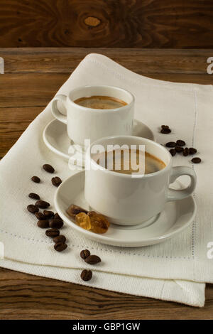 Due tazze di caffè e lo zucchero di canna sul tovagliolo di lino, verticale. Pausa caffè per due persone Foto Stock