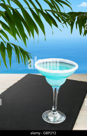 Cocktail blu sulla spiaggia tropicale. Blue Lagoon margarita martini cocktail. Estate spiaggia bere alcool. Iced cosmopolita blu Foto Stock