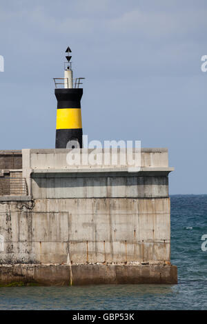 Faro e parete del porto a Comillas Spagna settentrionale Foto Stock