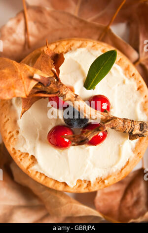 I biscotti con la crema di formaggio, mirtilli e asciugare le foglie di autunno intorno Foto Stock