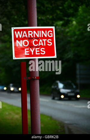 Il traffico che passa senza gatti occhi segno di avvertimento sulla strada al tramonto, Leeds Yorkshire Regno Unito Foto Stock