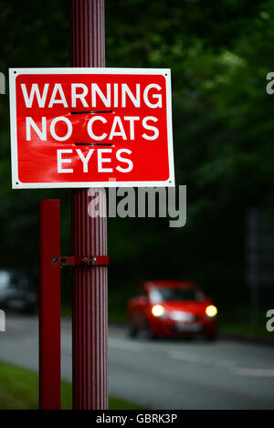 Il traffico che passa senza gatti occhi segno di avvertimento sulla strada al tramonto, Leeds Yorkshire Regno Unito Foto Stock