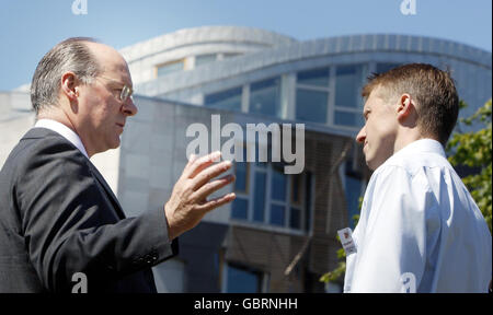 Il segretario alle finanze John Swinney (a sinistra) parla di fermare il attivista del Climate Chaos Mike Robinson al di fuori del Parlamento scozzese di Edimburgo, a seguito della decisione del MSP di sostenere un obiettivo più alto per il taglio dei gas serra. Foto Stock