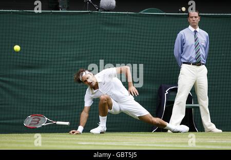 Roger Federer in Svizzera inciampa e cade durante la sua partita con Philipp Kohlschreiber in Germania durante i Wimbledon Championships 2009 presso l'All England Tennis Club Foto Stock