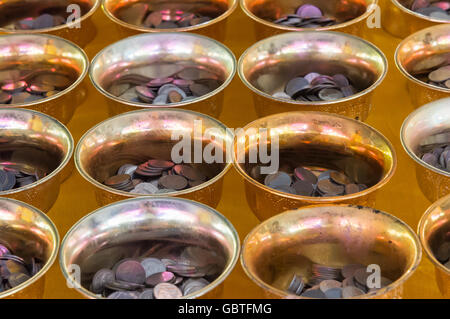 Vassoio d'oro piedistallo con piccola moneta per filantropia nel tempio thailandese, selezionare la messa a fuoco. Foto Stock