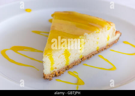 Limone torta di formaggio con salsa servita su una piastra bianca Foto Stock