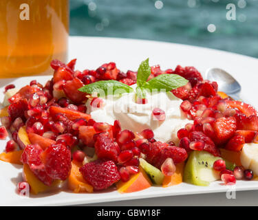 Holiday Colazione - yogurt greco, greco il miele, melograni, kiwi, pesche, fragole, prima colazione che si affaccia sul mare - Grecia Foto Stock