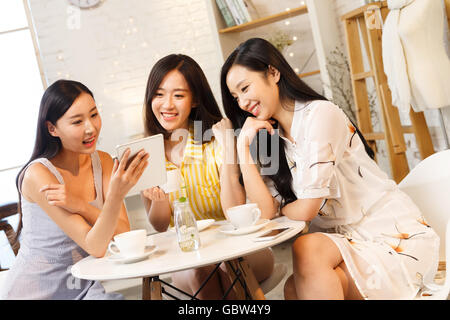 Giovani donne seduti in un caffè guardando un tablet Foto Stock
