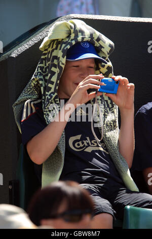 Uno spettatore scatta foto dell'azione con la sua macchina fotografica, durante i campionati di Wimbledon all'All England Lawn Tennis and Croquet Club, Wimbledon, Londra. Foto Stock