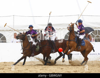 Le squadre si sfidano durante i British Beach Polo Championships da sotto gli impermeabile e gli ombrelloni nell'esclusiva area Sandbanks di Poole, Dorset. Foto Stock