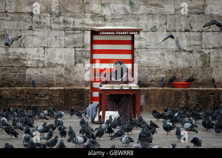 Una donna che indossa un copricapo vende i semi di uccelli su una piazza A Istanbul Foto Stock