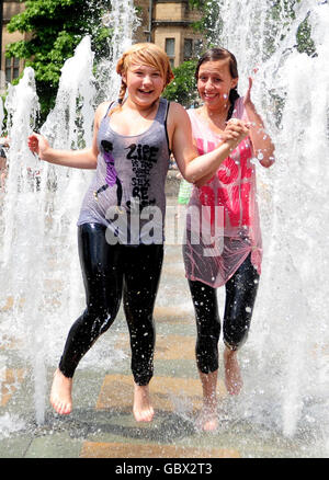 Jadie Randall (a sinistra) e Brenna Broughton si rinfrescano dal caldo nella fontana d'acqua nei Peace Gardens, Sheffield. Foto Stock