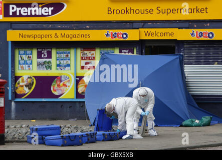 Gli ufficiali della polizia forense frequentano la scena a Salford, Manchester, dopo la sparatoria fatale di un uomo in un minimarket sabato sera. Foto Stock