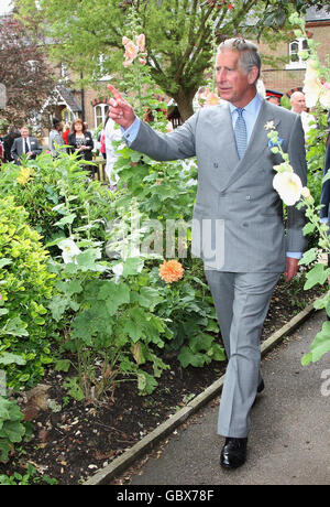 Il Principe del Galles, centro, patrono dell'Associazione Almshouse, cammina attraverso un'assegnazione durante una visita alle case di St Pancras nel nord di Londra per celebrare il 150° anniversario delle Almshouses. Foto Stock