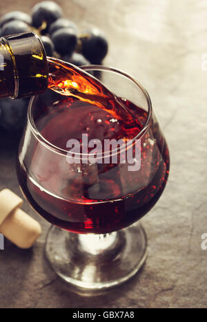 Vetro di cognac e uva sul tavolo Foto Stock