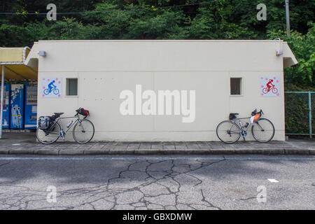 Due biciclette da strada parcheggiate fuori servizi igienici pubblici. Foto Stock