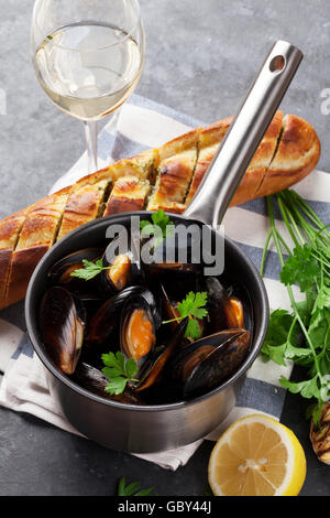 Le cozze in pentola di rame e vino bianco sul tavolo di pietra Foto Stock