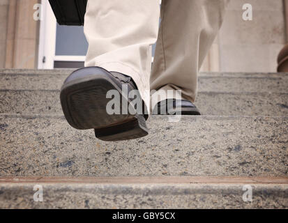 Un uomo di affari è scendendo le scale presso un ufficio per una potenza, sfida o il concetto di motivazione. Foto Stock