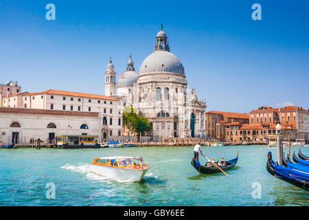 Gondola tradizionali e barca sul Canal Grande con la sua storica Basilica di Santa Maria della Salute in background, Venezia, Italia Foto Stock