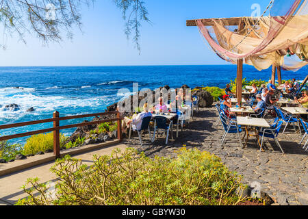 A Buenavista del Norte, TENERIFE, 15 NOV 2015: gente seduta in un ristorante sulla costa di Tenerife con oceano Atlantico in backgro Foto Stock