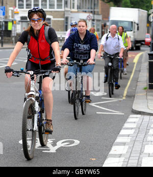 Un convoglio di ciclisti meno esperti segue un istruttore a King Street, Hammersmith, a ovest di Londra, mentre partecipa a un'iniziativa, sostenuta dal Sindaco di Londra e Transport for London, soprannominata "Cycle Fridays", per incoraggiare più pendolari a lavorare in bicicletta. Foto Stock