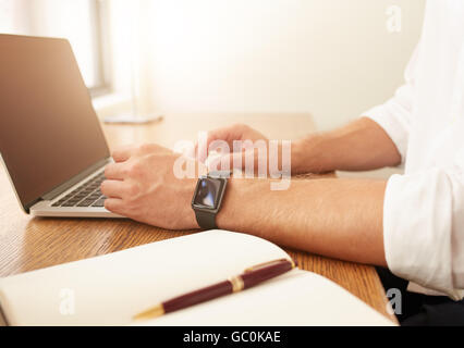 Chiudere l immagine dell uomo d affari lavorando sul computer portatile. Uomo con un smartwatch utilizzando computer portatile mentre è seduto alla sua scrivania. Foto Stock