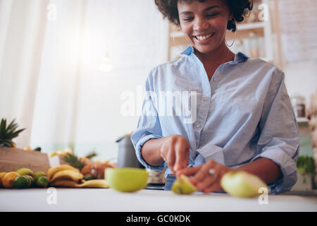 Ritagliato shot della donna africana frutti di taglio per la produzione di succhi di frutta al bar dei succhi. Foto Stock