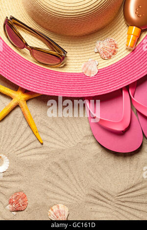 Concetto di estate con hat, flip-flop, conchiglie e occhiali da sole sulla spiaggia di sabbia sullo sfondo. Vista superiore Foto Stock