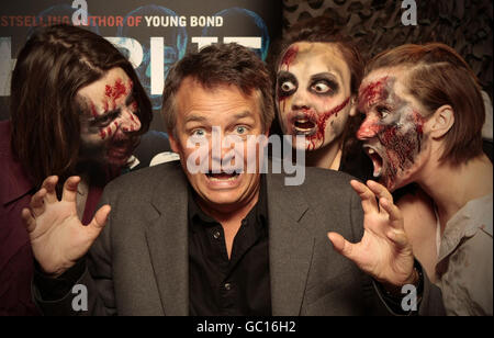 Il comico e autore Charlie Higson è circondato da "zombie" mentre firma le copie del suo nuovo libro per bambini "The Enemy" al London Bridge Experience. Foto Stock