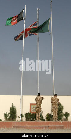 I soldati abbassano la bandiera dell'Unione e la bandiera delle Brigate leggere del 19 (destra) a metà albero in memoria delle vittime britanniche del 200esimo e 201esimo incidente a Lashkar Gah, nella provincia di Helmand, in Afghanistan. Foto Stock