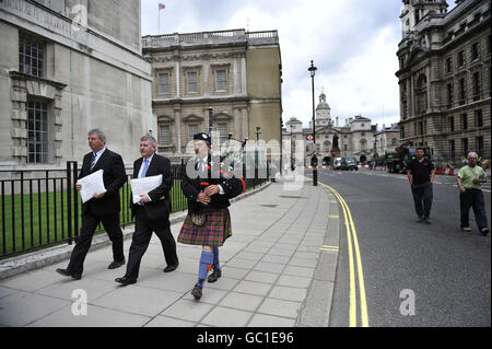 (Da sinistra) Angus Campbell, presidente della Hebrides Range Taskforce, Angus MacMillan, Il presidente di Storas Uibhist e il piper James MacKay marciano lungo Whitehall per consegnare lettere al Ministero della Difesa e al governo per combattere contro i piani per ridimensionare un campo di prova delle armi nelle Ebridi esterne che comporterà la perdita di posti di lavoro. Foto Stock