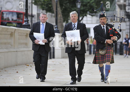 (Da sinistra) Angus Campbell, Presidente della Hebrides Range Taskforce, Angus MacMillan, Il presidente della Storas Uibhist e il piper James MacKay marciano lungo Whitehall per consegnare lettere al Ministero della Difesa e al governo per combattere contro i piani di ridimensionamento di un campo di prova delle armi nelle Ebridi esterne che causeranno la perdita di posti di lavoro. Foto Stock