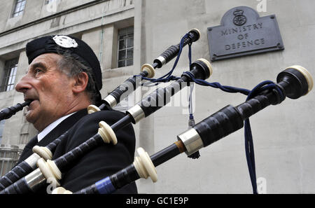 Piper James MacKay al di fuori del Ministero della Difesa di Londra, dove la Hebrides Range Taskforce ha consegnato lettere al mod e al governo per combattere contro i piani di ridimensionamento di un campo di prova delle armi nelle Ebridi esterne, che causeranno perdite di posti di lavoro. Foto Stock