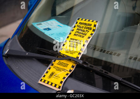 Un parcheggio auto penalità fissa avviso ticket, in gallese e lingua inglese, sul parabrezza di una vettura che ha anche un blue badge disabili Wales UK Foto Stock