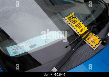 Un parcheggio auto penalità fissa avviso ticket, in gallese e lingua inglese, sul parabrezza di una vettura che ha anche un blue badge disabili Wales UK Foto Stock