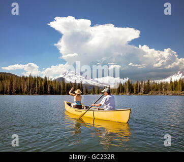 Una coppia di sposi, cittadini anziani, canoe camping sul lago di scintille in Oregon Cascade Mountains lungo la cascata autostrada dei Laghi. Sorelle deserto e Sud sorelle picco sono in background. Foto Stock