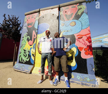 Il grande britannico Phillips Idowu pone con il suo allenatore Aston Moore, per i media al muro di Berlino dopo aver tenuto una conferenza stampa su un autobus turistico all'aperto durante i Campionati del mondo IAAF all'Olympiastadion, Berlino. Foto Stock