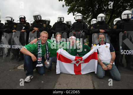 La polizia in attrezzatura da sommossa continua a guardare mentre i tifosi dell'Irlanda del Nord posano per i fotografi e fuori dallo stadio prima della partita di qualificazione europea della Coppa del mondo allo Slaski Stadium di Chorzow, Polonia. Foto Stock