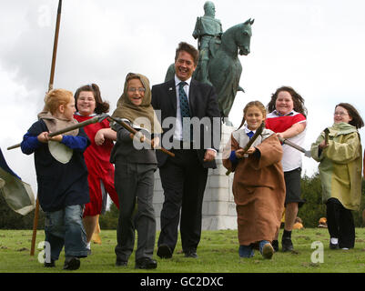 Il ministro delle scuole Keith Brown con i bambini della scuola elementare di St Ninian alla statua di Robert Bruce al Bannockburn Heritage Center di Stirling, dove ha annunciato il finanziamento di viaggi scolastici in siti storici tra cui Culloden e il luogo di nascita di Robert Burns. Foto Stock