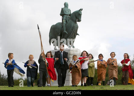 Il ministro delle scuole Keith Brown con i bambini della scuola elementare di St Ninian alla statua di Robert Bruce al Bannockburn Heritage Center di Stirling, dove ha annunciato il finanziamento di viaggi scolastici in siti storici tra cui Culloden e il luogo di nascita di Robert Burns. Foto Stock