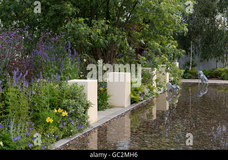 Una grande fontana, erbaceo frontiere e sculture del cane in cani fiducia: una vita cani Giardino Foto Stock