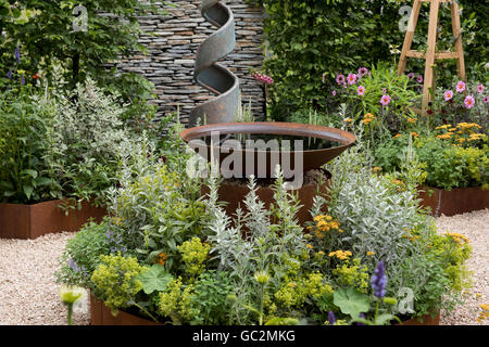 Piantando naturalistica intorno a un metallo caratteristica dell'acqua nel rifugio estivo giardino all'Hampton Court Palace Flower Show 2016 Foto Stock