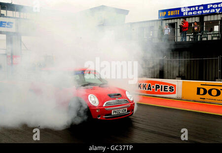 Un pilota Mini si prepara a gareggiare contro una polizia britannica Subaru Impreza WRX che si è rimboccata come un'auto di polizia statunitense, durante 'Beat the Heat' a Santa Pod Race Way, Wellingborough, Northamptonshire. Foto Stock