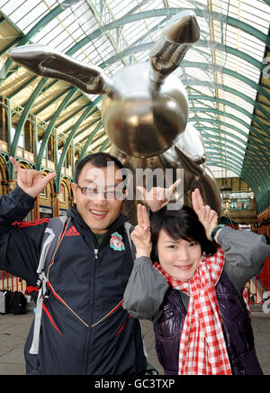 I turisti posano per i fotografi come il gigante palloncino di coniglio dell'artista Jeff Koons 53 piedi è esposto a Covent Garden Market per pubblicizzare Pop Life: Art in a Material World a Tate Modern, Londra. Foto Stock