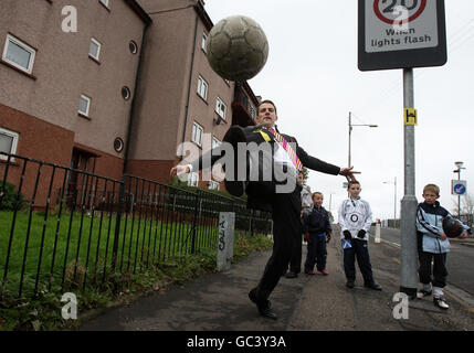 Il candidato della SNP David Kerr calcia un calcio con alcuni bambini locali nelle strade della zona di Milton a Glasgow, mentre aiuta a lanciare la campagna di by-elezione di Glasgow Nord Est. Foto Stock